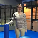 Cristina-Gónzalez una mujer en un estudio de fitness o fisioterapia, junto a un rodillo de espuma azul.