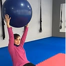 Esther-Alamancos una persona haciendo ejercicio en el suelo con una pelota de ejercicios azul.
