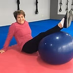 Ines-Carrón una persona haciendo ejercicio en el suelo con una pelota de ejercicios azul.