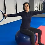 Ines-Vilamea persona realizando un ejercicio de Pilates o entrenamiento funcional utilizando una pelota de estabilidad (fitball o balón suizo) y bandas de resistencia tipo TRX.